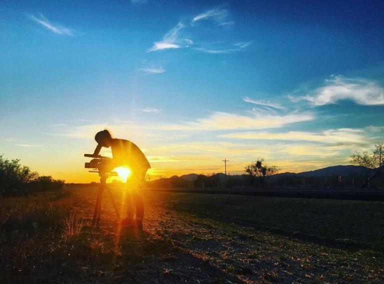 Sandra Westdahl setting up a video camera at sunset. Sandra Westdahl setting up a video camera outside with sunset in the background.